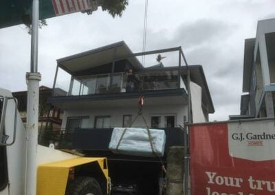 mobile franna crane lifting furniture up 3 storeys over balcony northern beaches
